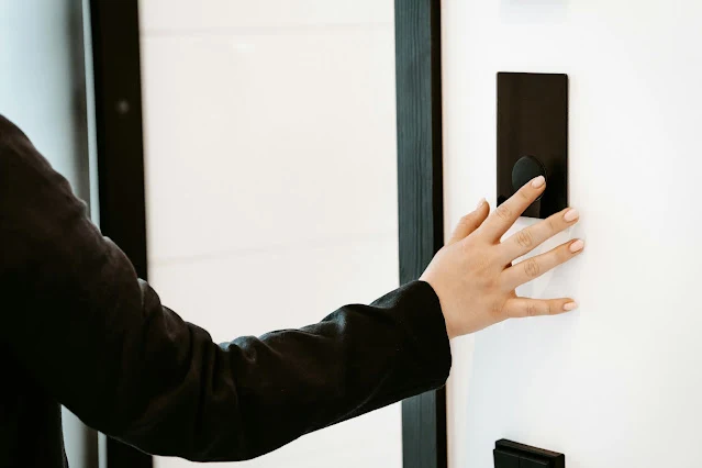 A hand touching a smart access panel beside a modern door